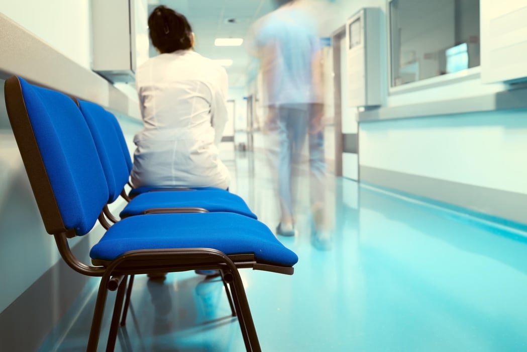 Female doctor sitting on the chair in the hospital corridor.