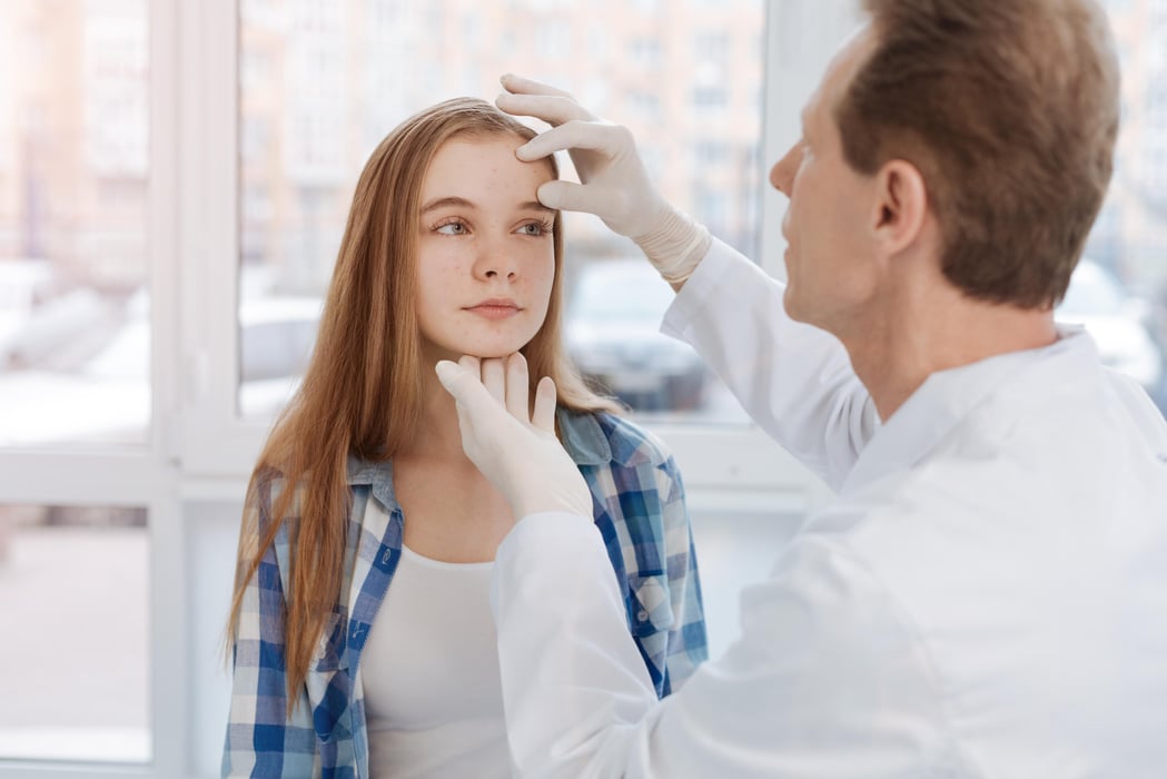 Aged dermatologist touching patient face in the clinic