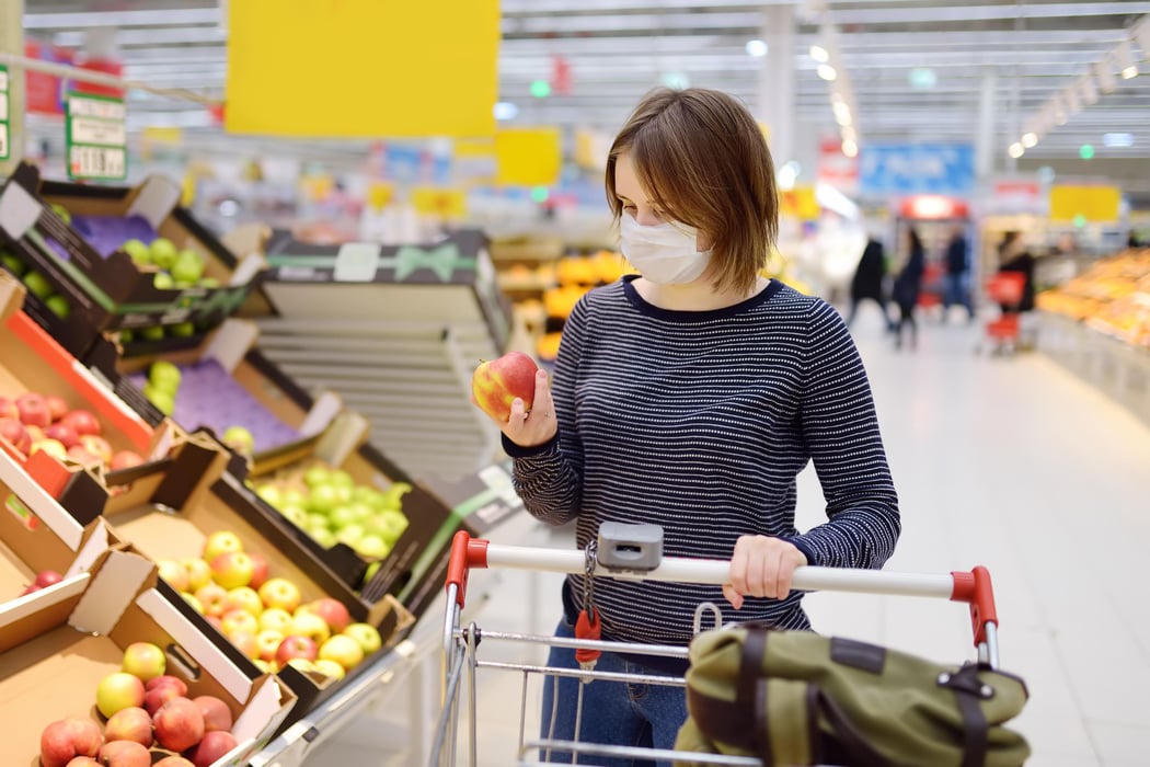 Young woman wearing disposable medical mask shopping in supermarket during coronavirus pneumonia outbreak