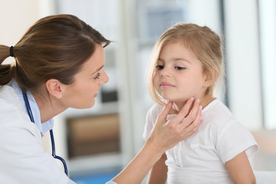 Pediatrician in office checking on child's throat