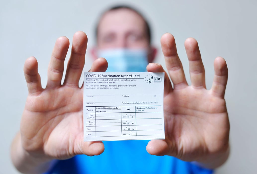 male is holding a vaccination record card and corona virus vaccine vials. Passport of immunity to the coronavirus in the hands of a male. Health passport as proof of recovery from COVID-19.