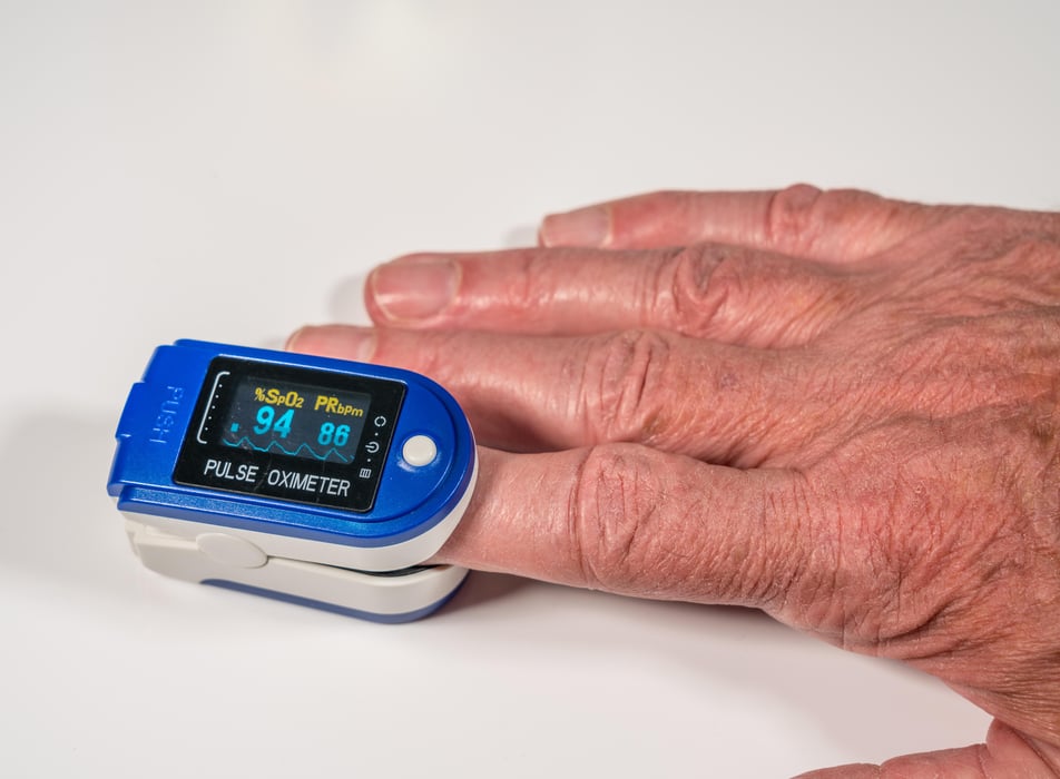 Senior man using a pulse oximeter on finger to test blood oxygen level