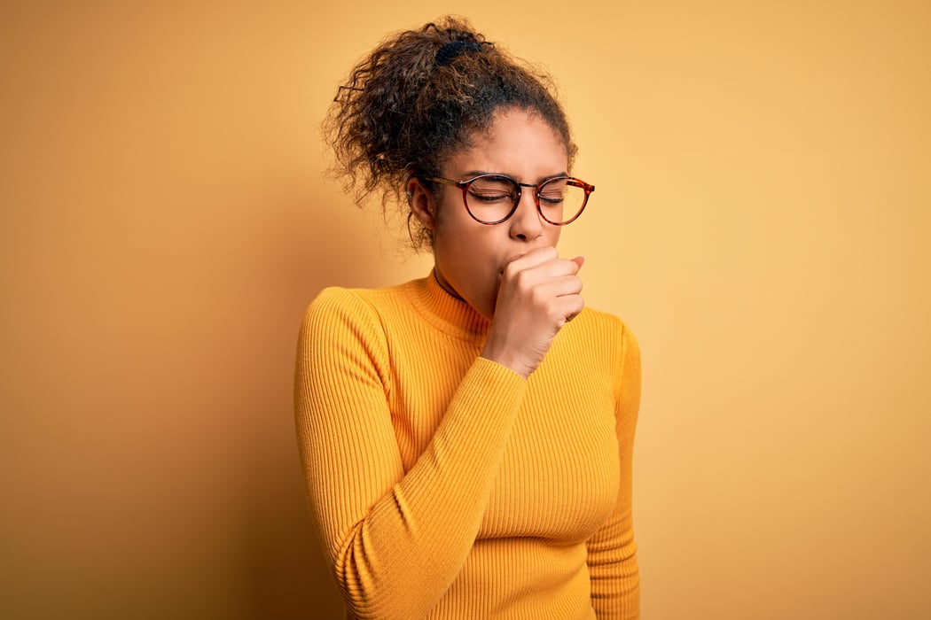 Young beautiful african american girl wearing sweater and glasses over yellow background feeling unwell and coughing as symptom for cold or bronchitis. Health care concept.