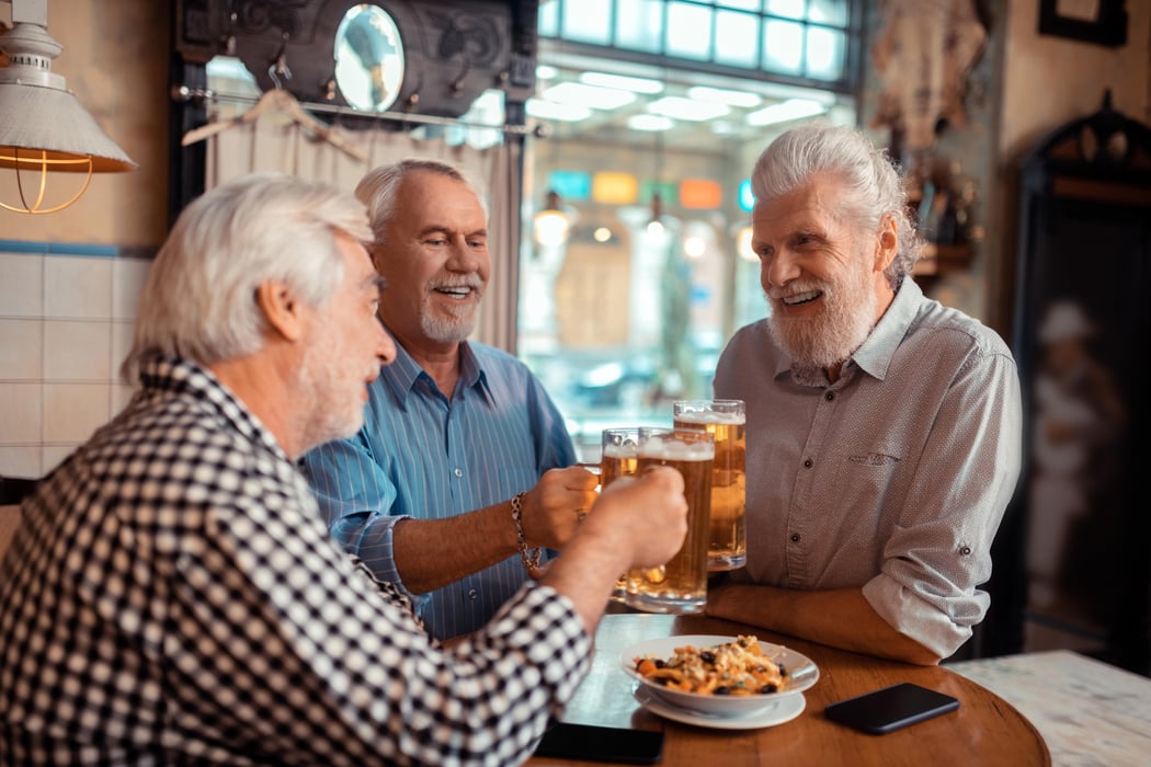 Positive pensioners clanging their glasses with beer