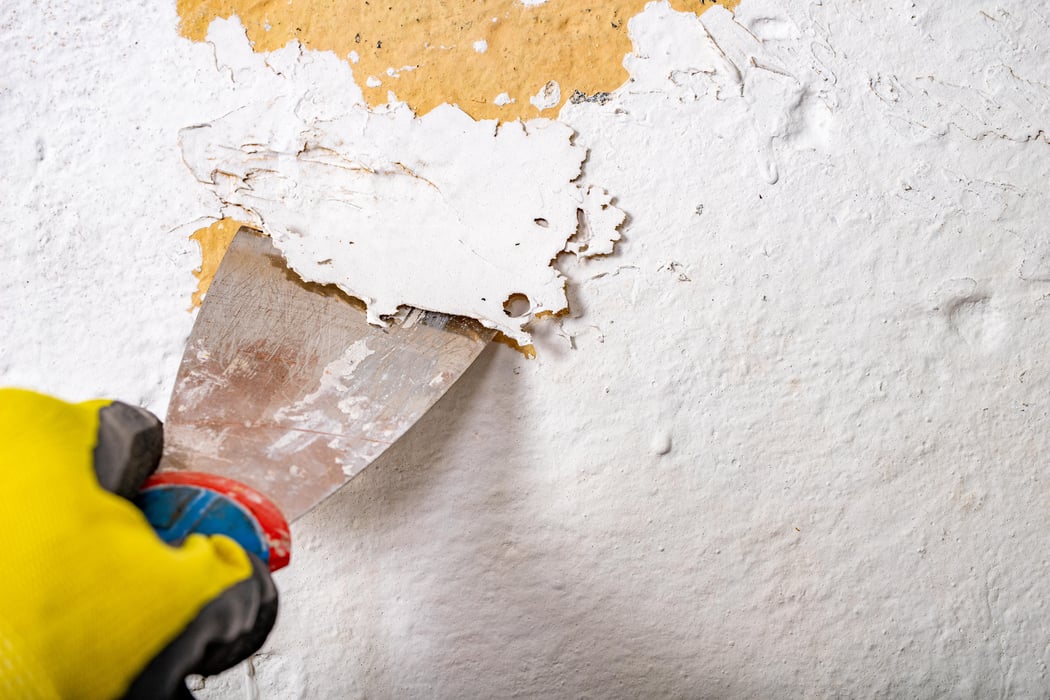 Removing old paint from the wall with a metal spatula. Small painting works at home.
