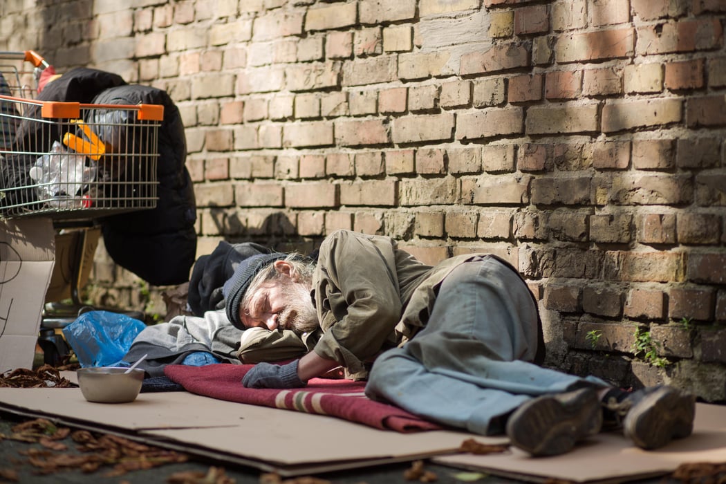 Sleeping homeless man lying on cardboard.
