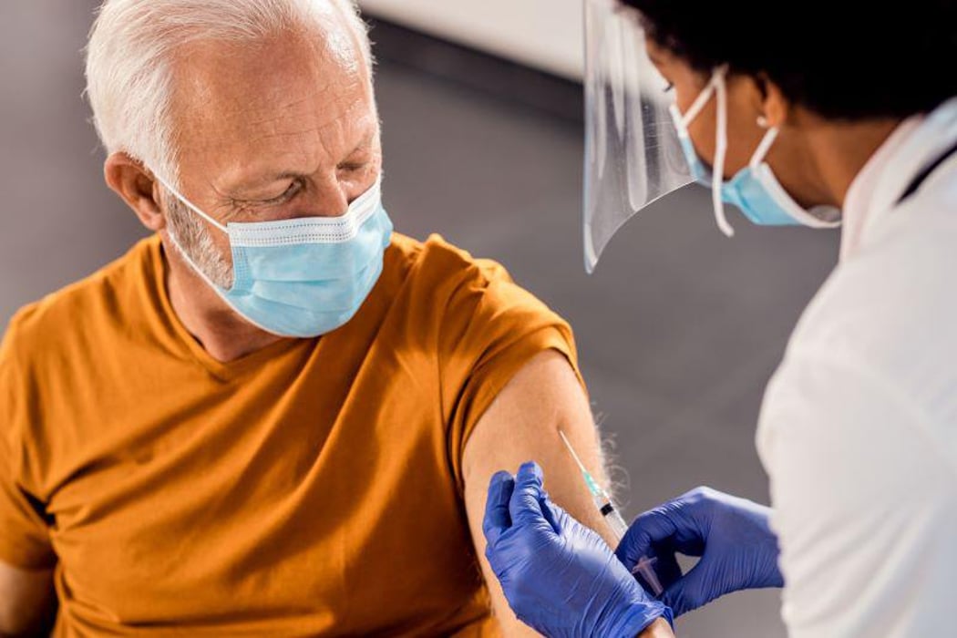A man receiving a vaccine with a needle in his arm