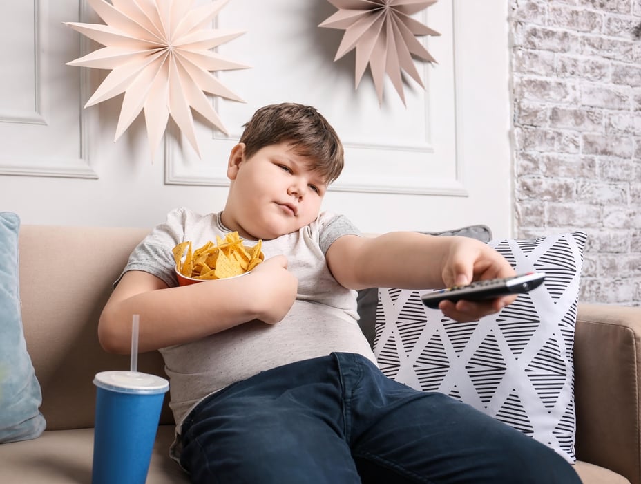 obese boy eating and watching TV
